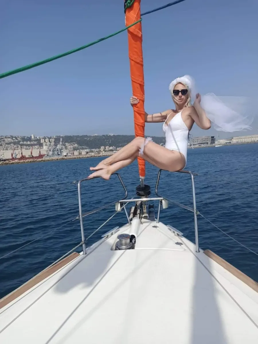 כלה לעתיד בבגד ים לבן והינומה מצטלמת על חרטום היאכטה.